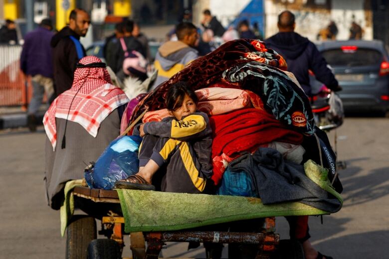 A child sits on a trailer, as Palestinians flee their homes in Khan Younis, in the Gaza Strip, amid Israeli airstrikes.