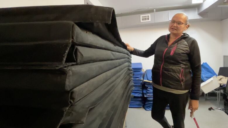 A woman stands by a set of stacked sleeping maps.