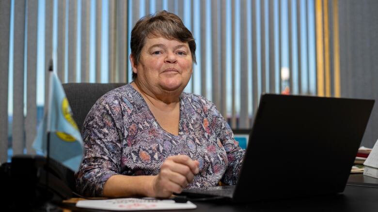 A woman sits at a desk on a computer.