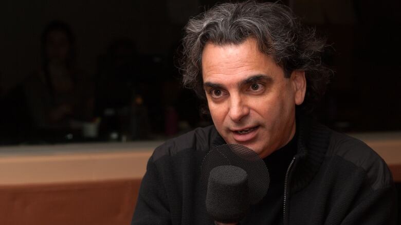  A man speaking into a microphone in a radio studio. 