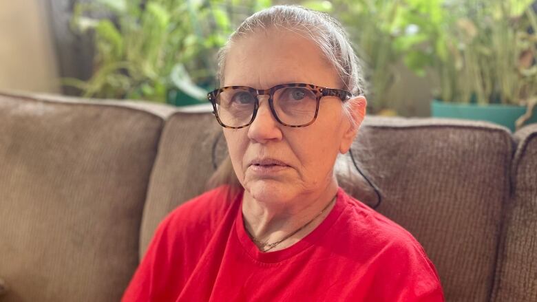 Woman sits on couch holding documents