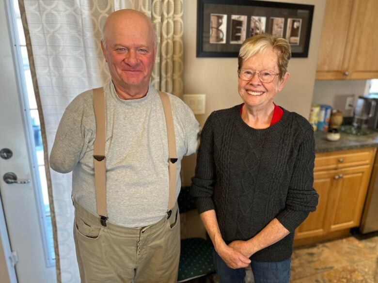 Bald man with no arms stands beside woman with blonde short hair.