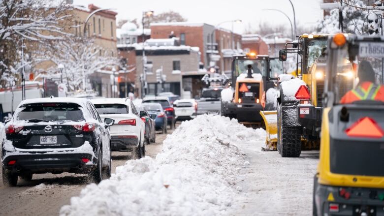 City workers driving small snowplows to clear snow after a snowstorm.