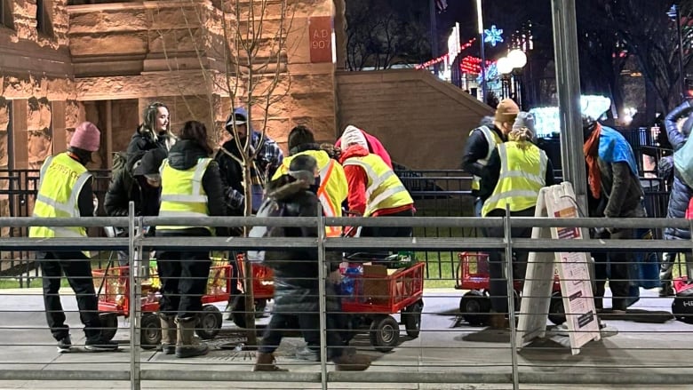 Men and women wear bright yellow construction vests and distribute food, clothing and other items  to the city's most vulnerable .