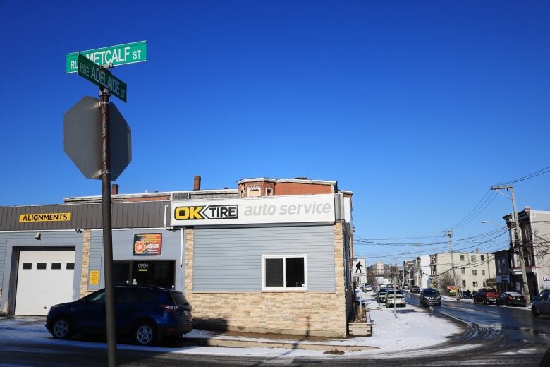 A winter scene of an auto service shop on a snow-covered, otherwise residential, street. 