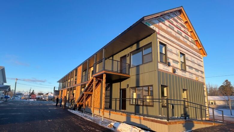 A two story apartment building still under construction. It is dark green with wood. Siding is not finished. 