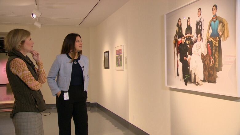 Two women looking at art works in an art gallery.