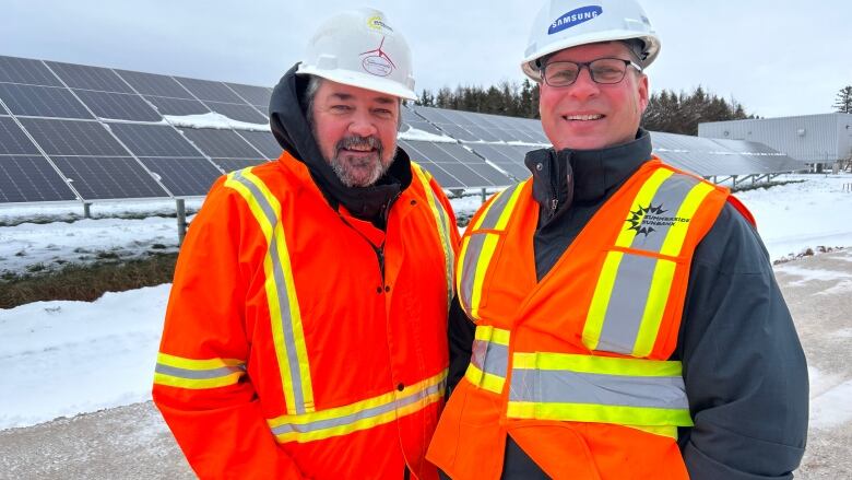 City officials Mike Thususka and Greg Gaudet stand by large solar panels.