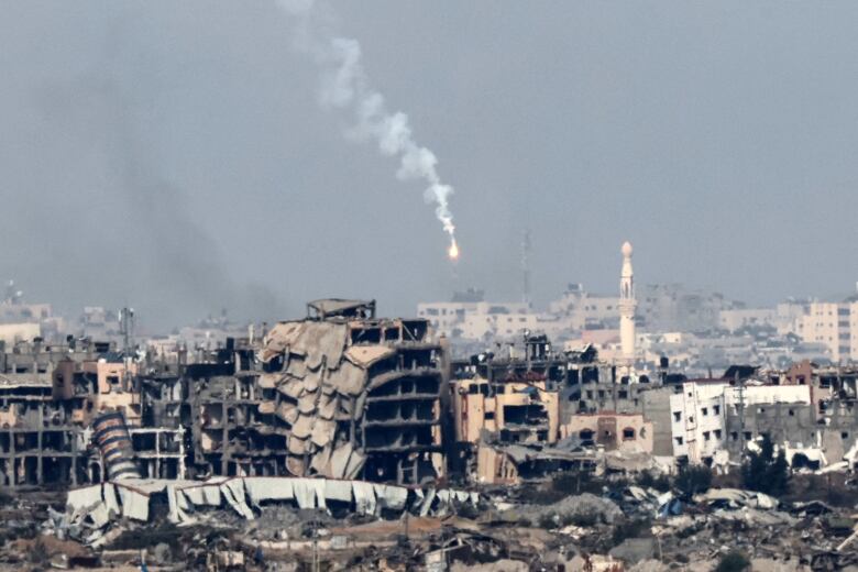 A flare is seen above destroyed buildings.