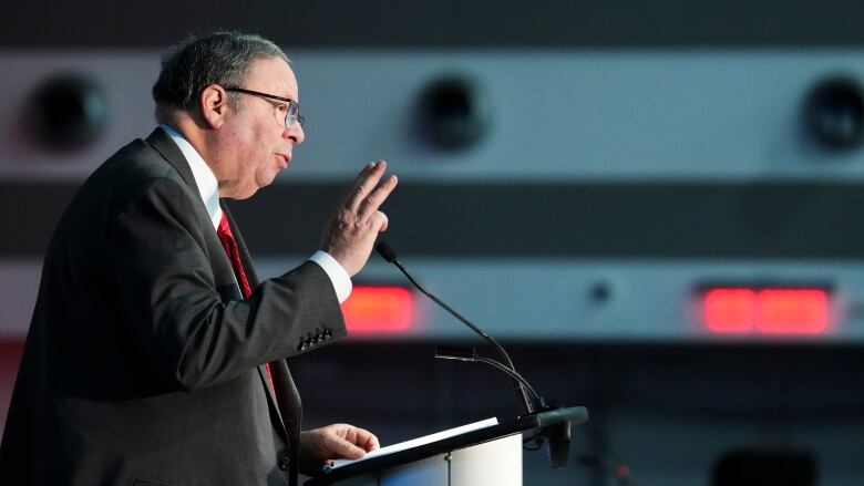 Profile shot of man in suit speaking at podium