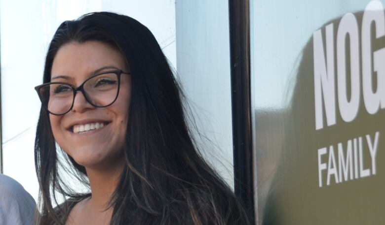 A woman with dark hair and glasses smiles