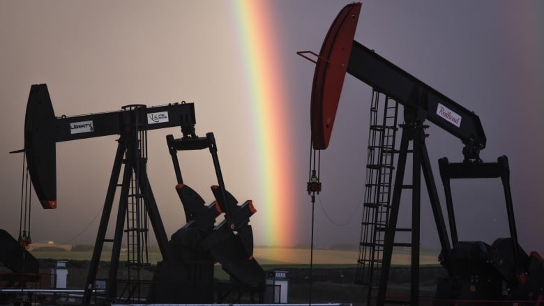 Two pumpjacks are seen, with a rainbow pictured in the background.