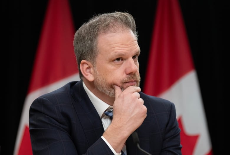 Health Minister Mark Holland listens to a question from a reporter during a news conference.