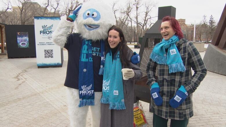 Two women standing with a mascot