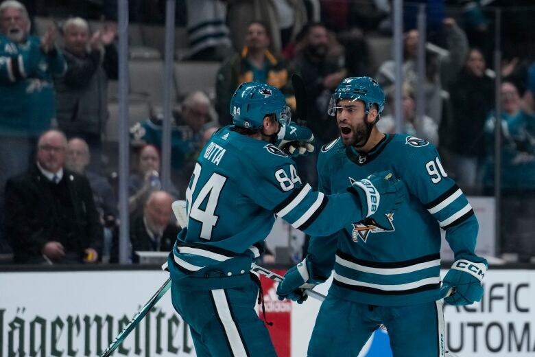 Two San Jose Sharks players celebrate on the ice.