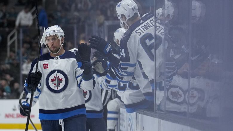 Winnipeg Jets player high-fives players on the bench.