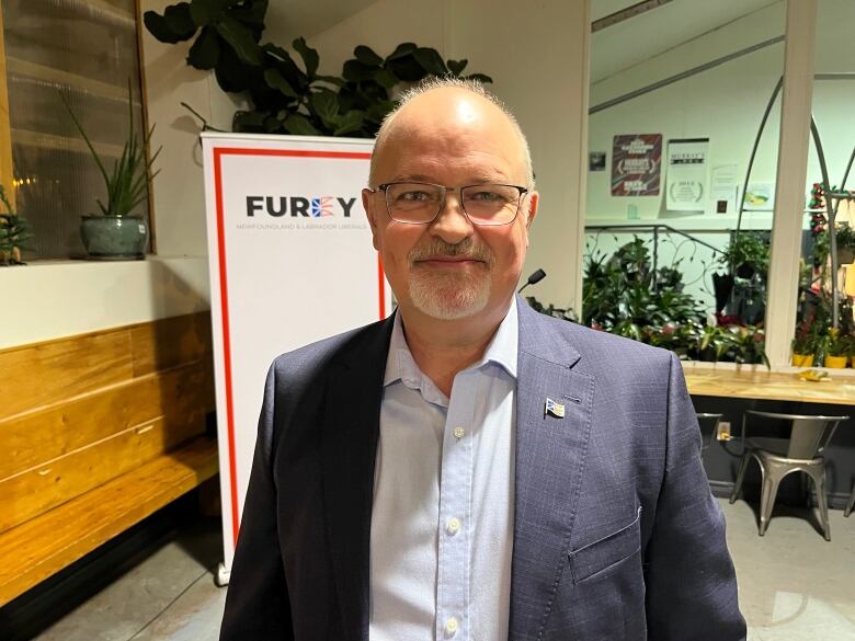 A smiling man wearing glasses and a suit.