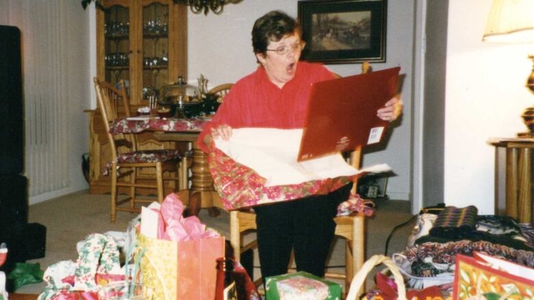 An old photo of a woman opening a calendar as a Christmas gift.