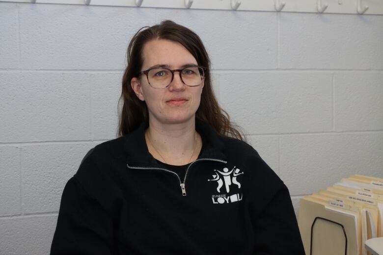 Christine Richardson wears a black Jeunesse Loyola sweater, glasses and has her hair down. This is a portrait of her