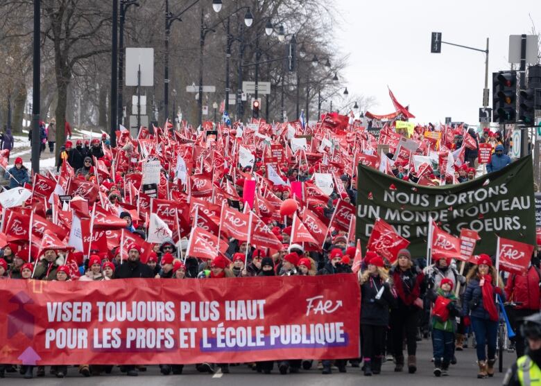 Hundreds of FAE members wave rave flags and march behind a banner. 