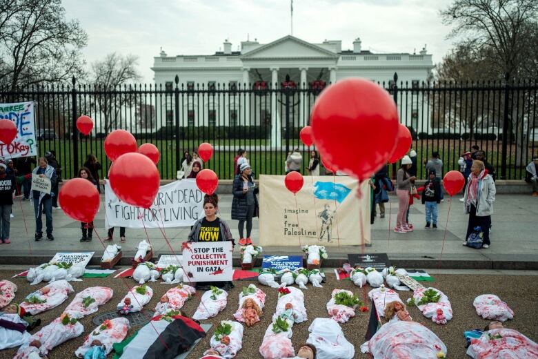 People and dolls lying on the floor in front of the White House, referring to civilian deaths in Gaza