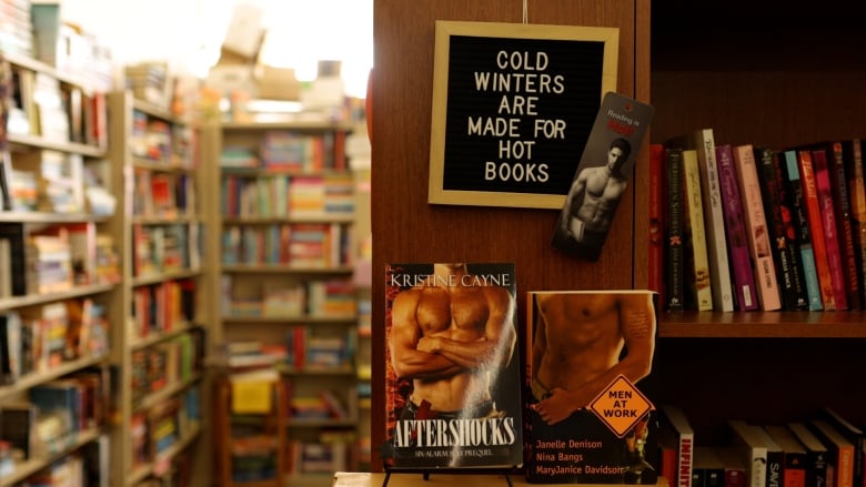 Two romance books are on display with a sign above that reads, cold winters are made for hot books.