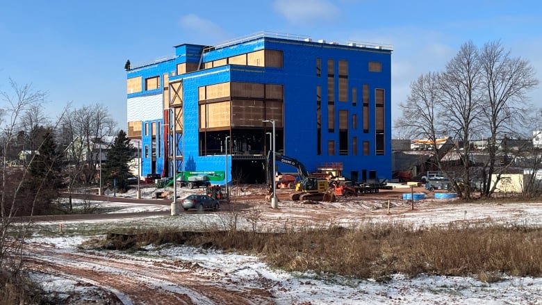 Large building under construction surrounded by heavy machinery.