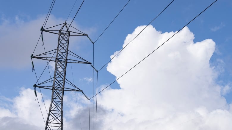 Hydro transmission towers are seen amid a blue sky with white clouds.