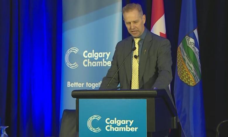 A man stands behind a podium wearing a suit.