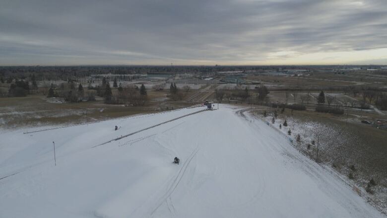 A ski hill with man-made snow on it surrounded by a dry city.