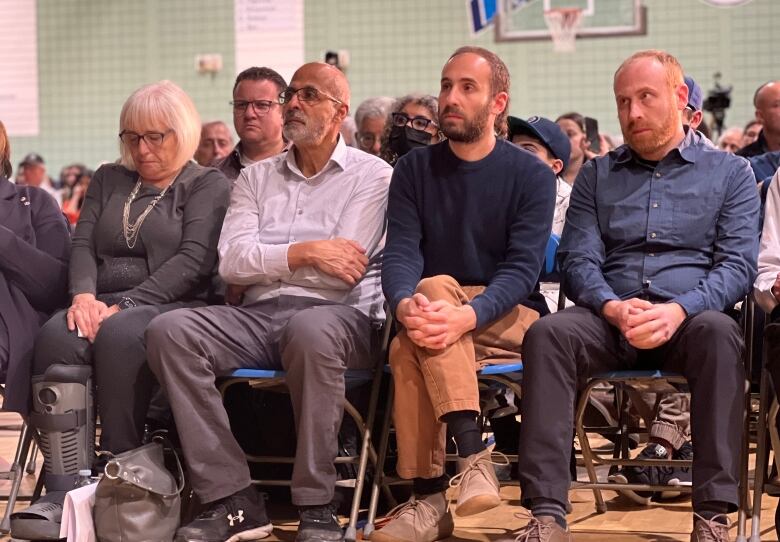 Four people sitting in chairs inside a gymnasium