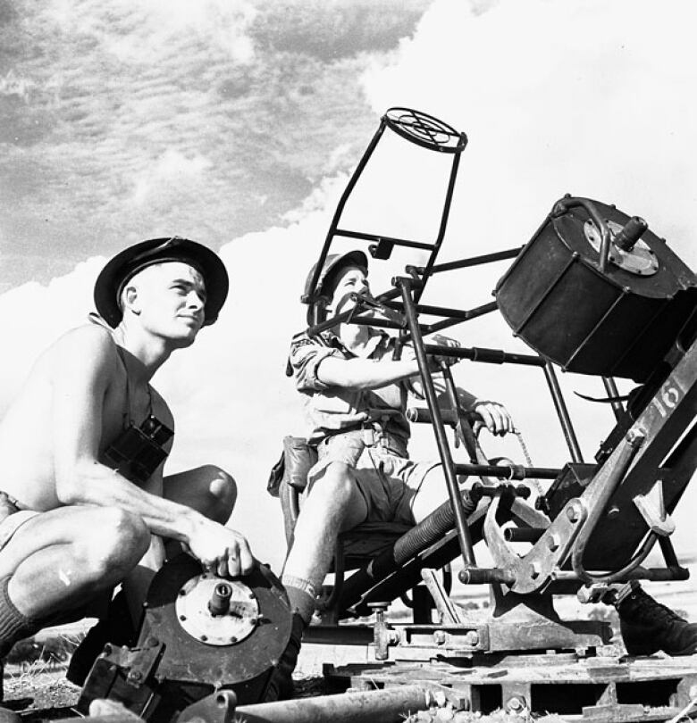 Two Canadian Second World War soldiers man an anti-aircraft gun in a black and white photo from Italy in October 1943.