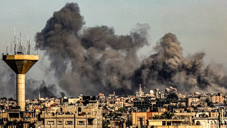 Black smoke billows above a city.