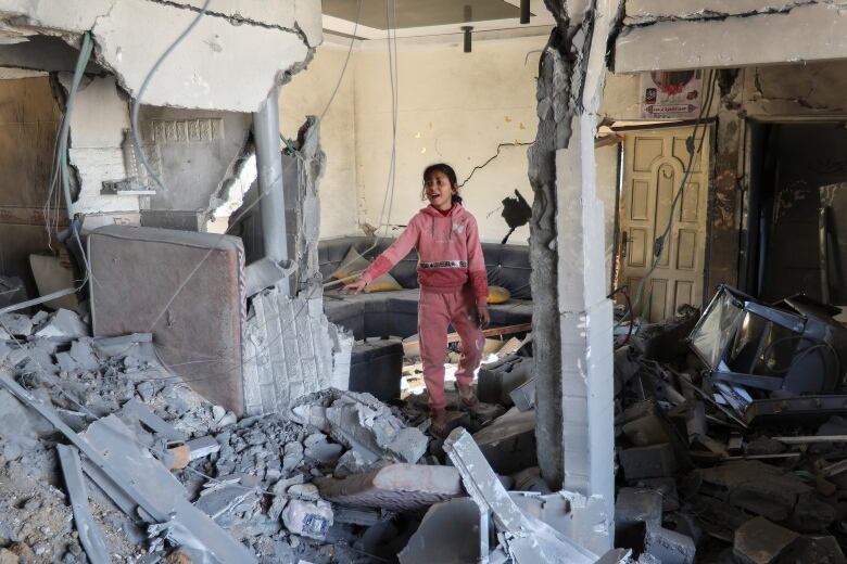 A child is seen amid the rubble of a destroyed home.