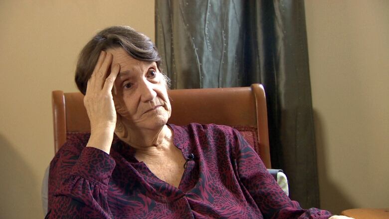 An elderly woman sits in a chair