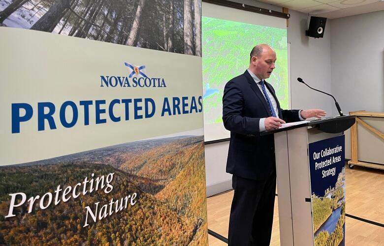 A bald man stands at a podium.