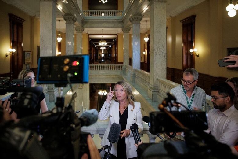 Marit Stiles is pictured surrounded by reporters and tv cameras in a corridor at the Ontario Legislature.