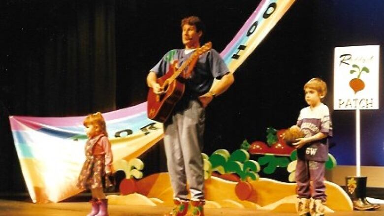 A man on stage with two kids.