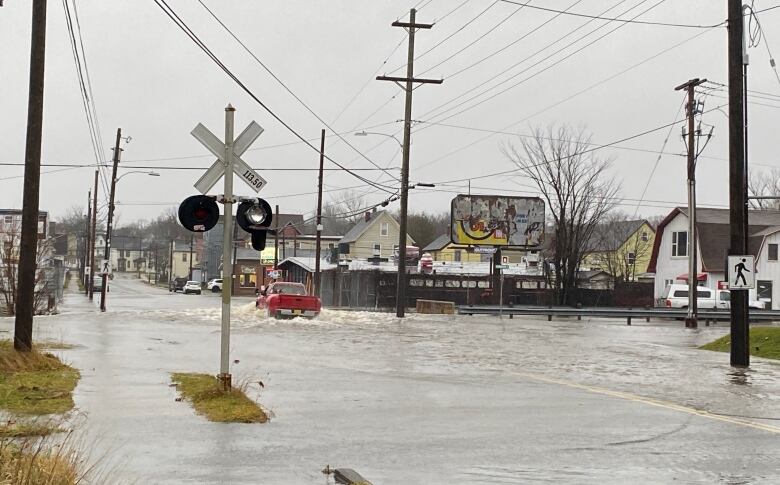 A red pickup is shown driving through a flooded street.