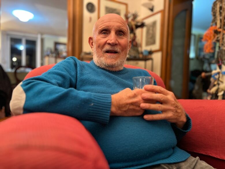 A man sitting in a chair, holding a glass. 