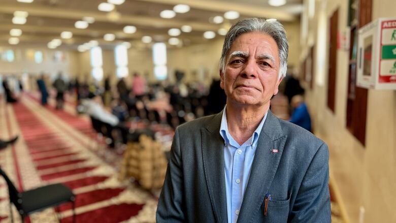 A portrait of a man in a suit jacket in a mosque. 