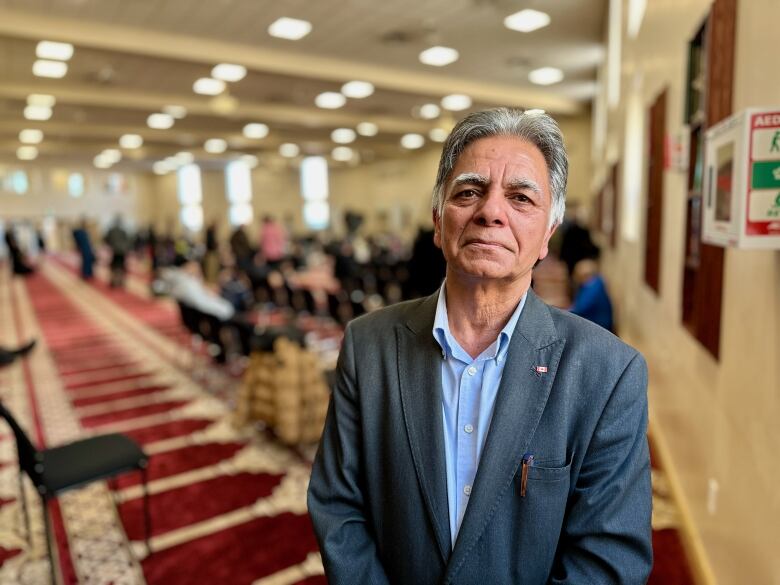 A portrait of a man in a suit jacket in a mosque. 