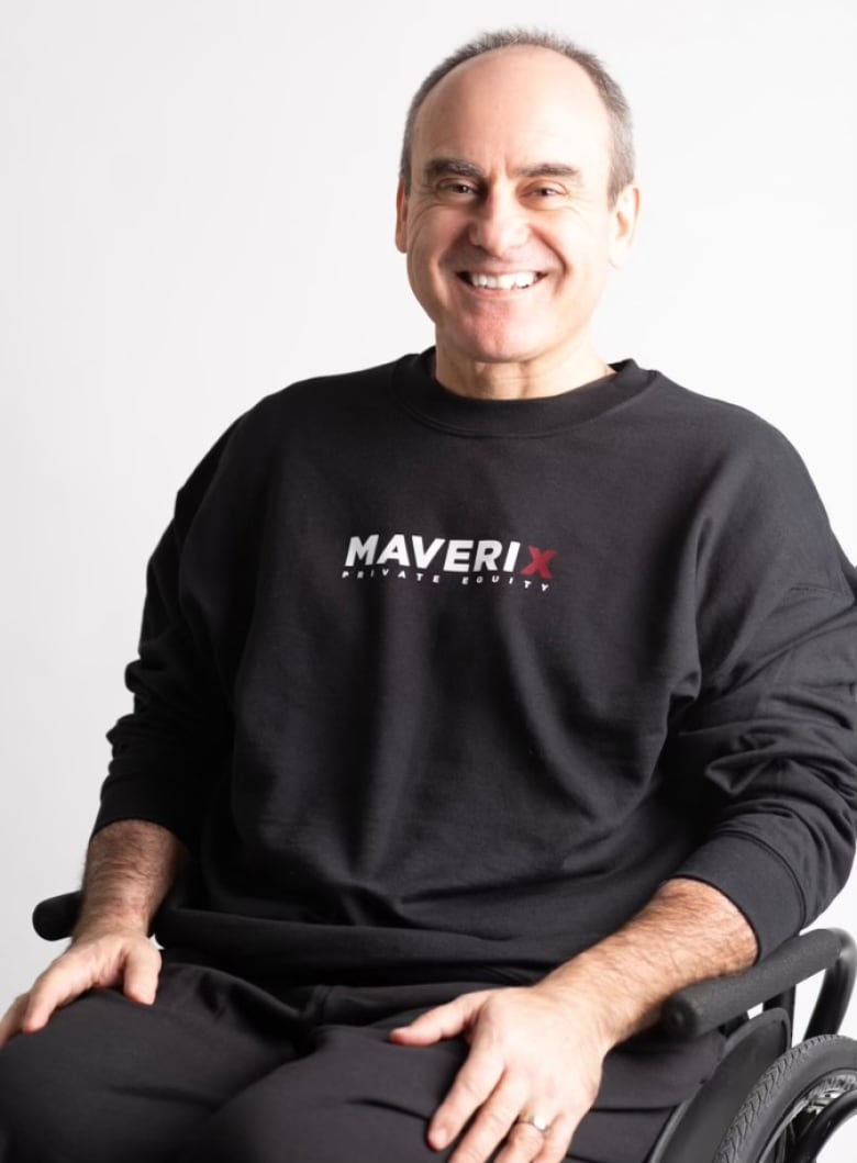 Man smiling in his wheelchair while wearing a Maverix shirt.