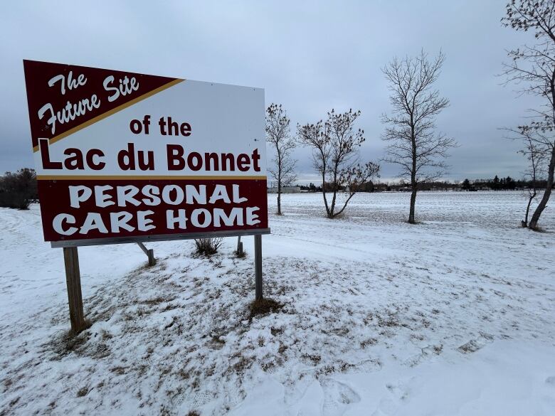 A sign that says future site of the Lac du Bonnet personal care home stands in a field partially covered with snow.