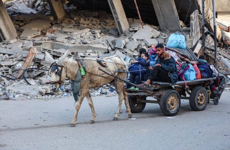 Palestinians ride on a cart with their belongings.