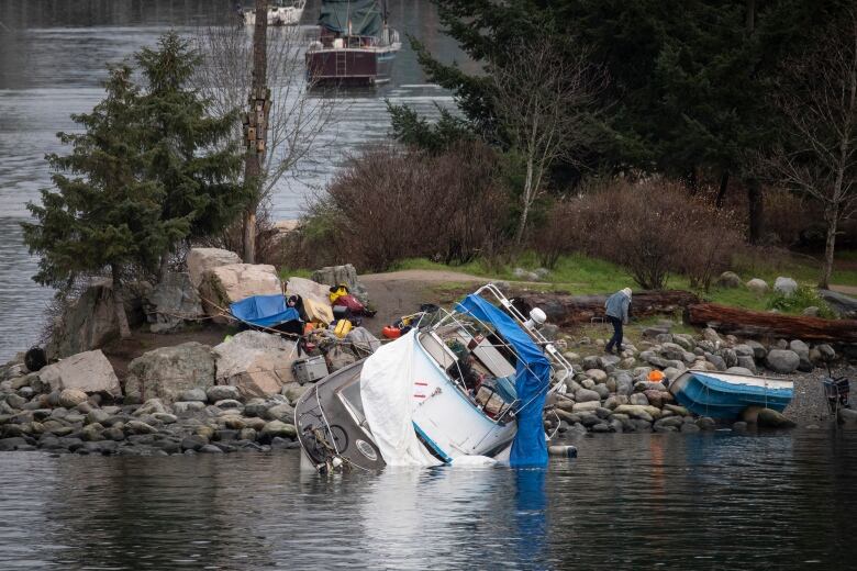 A boat on its side against a rocky shore