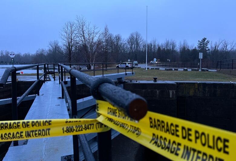 Police tape with police cars in the background.