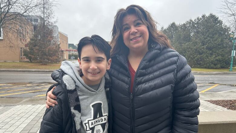 a woman and her son smiling at the camera 