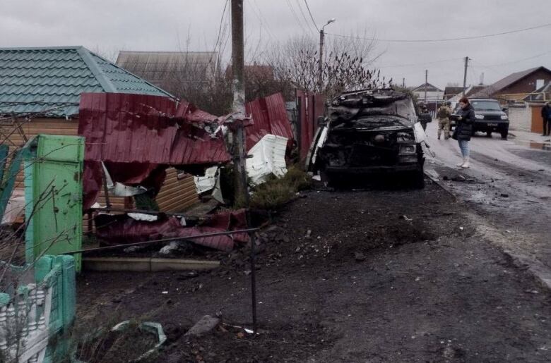 A damaged building and car is shown.