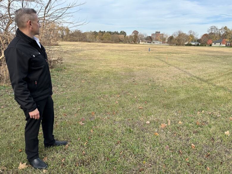 A man stands looking out at a field